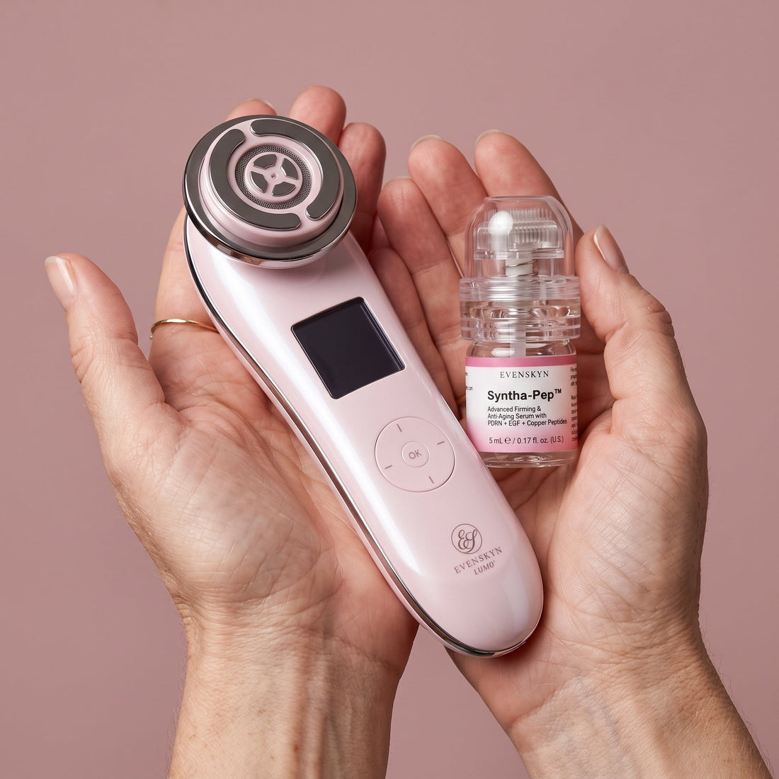 Open palms holding the pink EvenSkyn Lumo+ handset and a Syntha-Pep serum vial with a MicroInfuser needle head