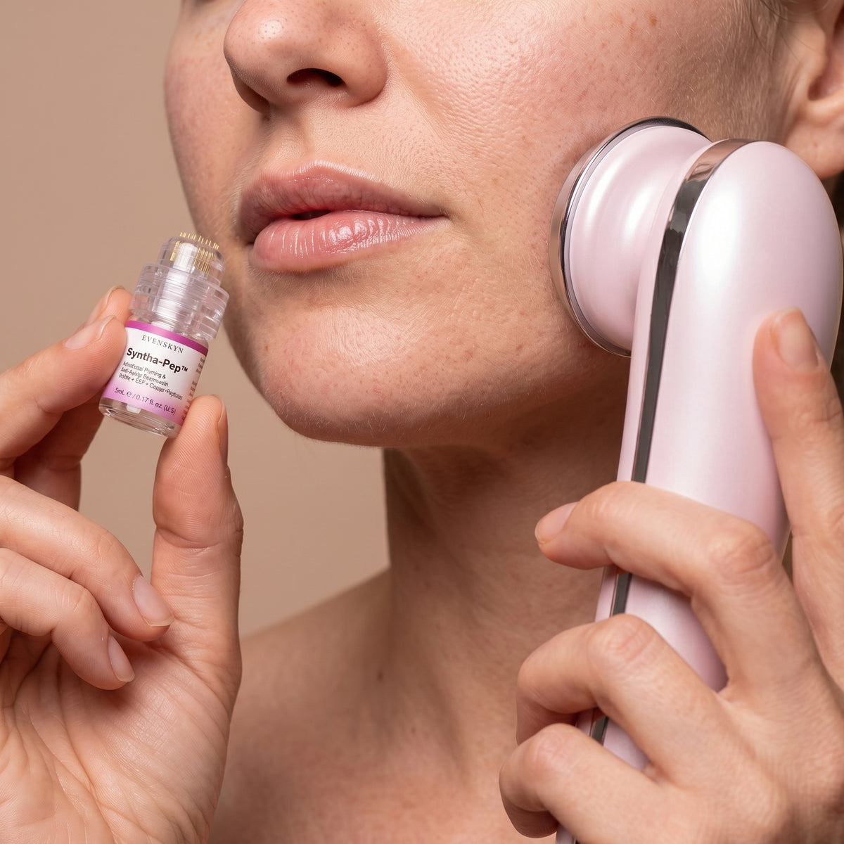 Close-up of a woman holding the Syntha-Pep serum vial with MicroInfuser stamp head near her lips while the treatment head of a pink Lumo⁺ handset rests on her cheek